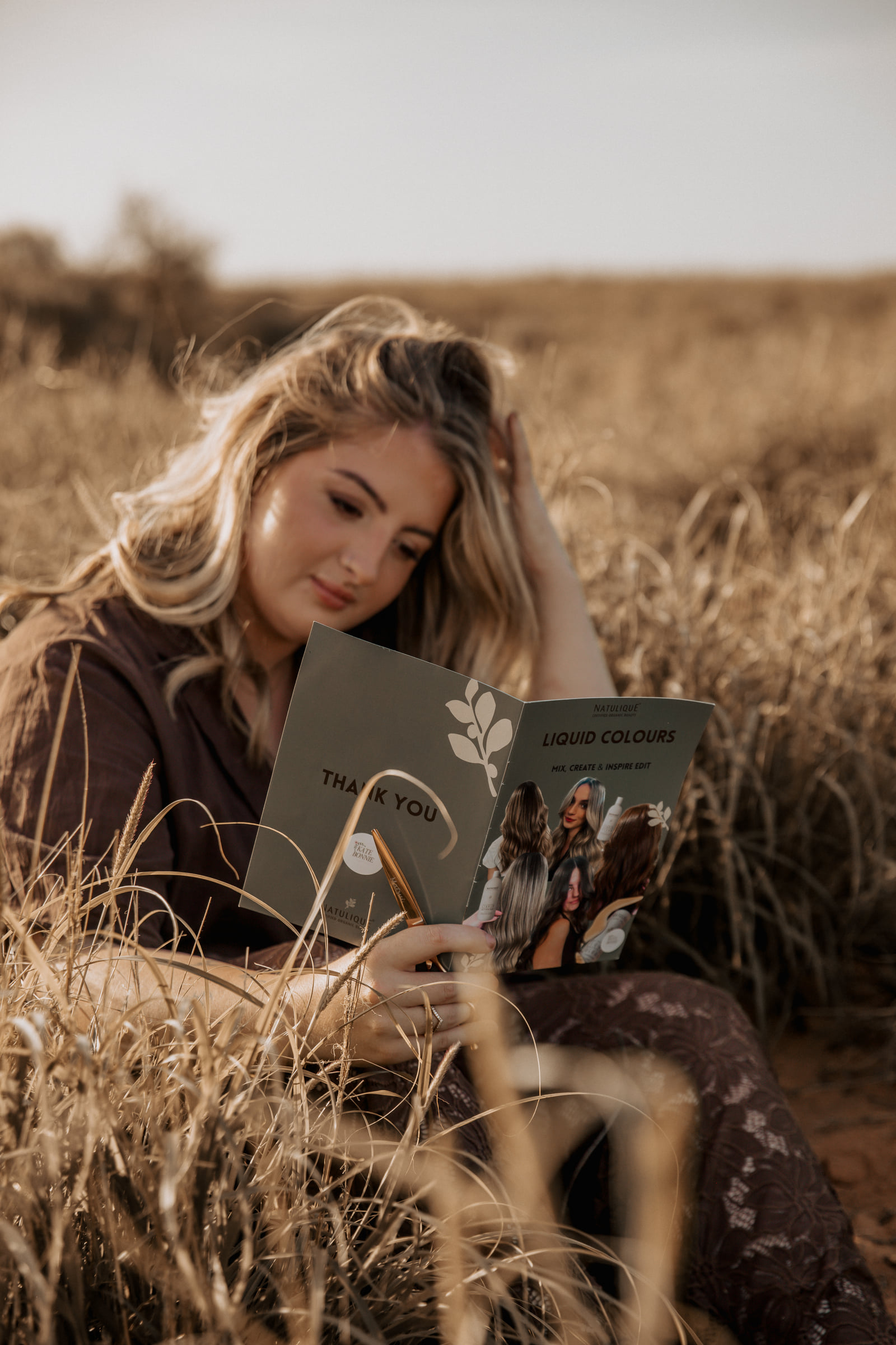 Kate Bonnie reading hair colour education book in Pilbara grassland South Hedland